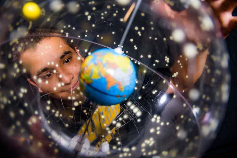 A Boy looking at a globe with a smile on his face