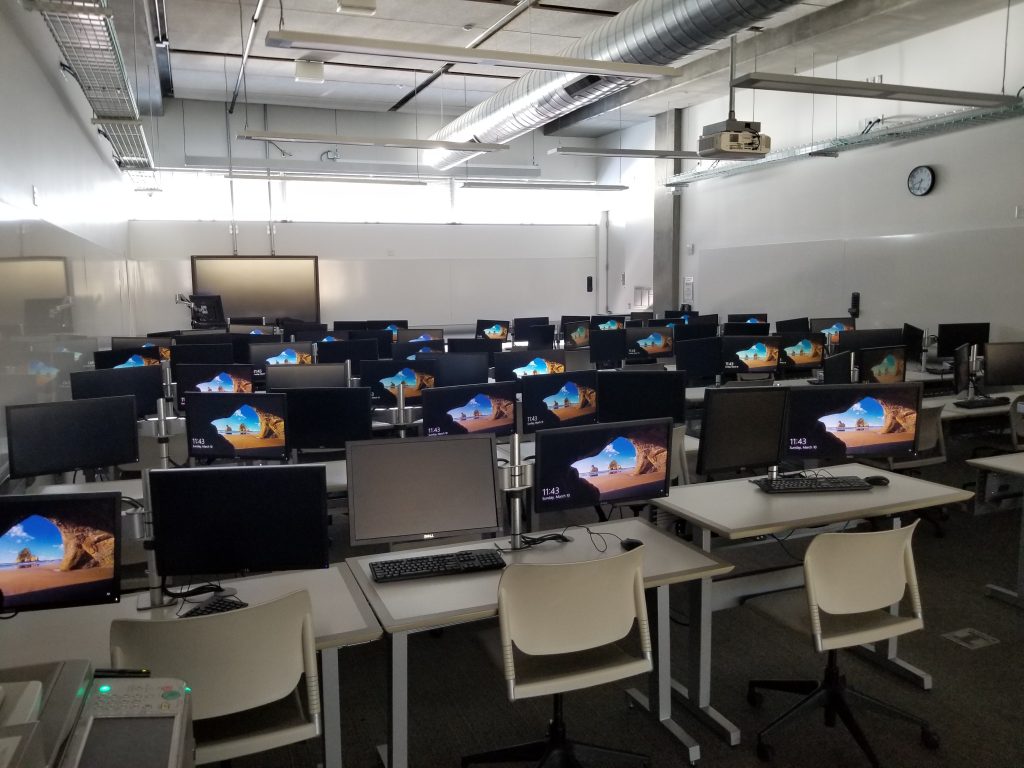 A lab that has several rows of mac monitors and an instructor station.
